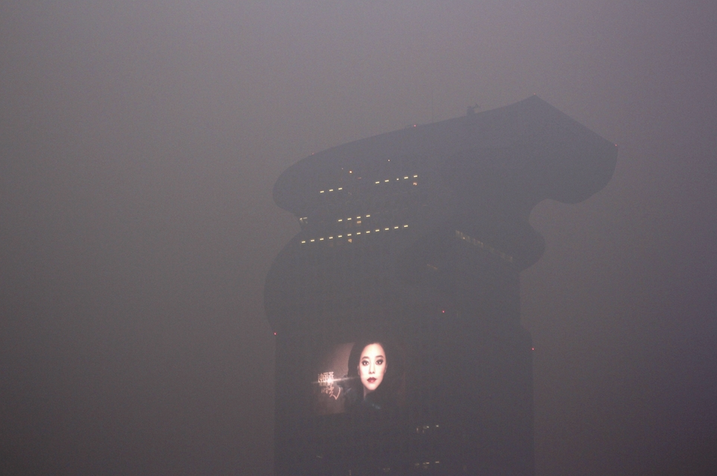 Foggy picture of Pangu Hotel in Beijing in 2013, looking a lot like Blade Runner's iconic giant screens on skycrapers showing an ad with a Geisha
